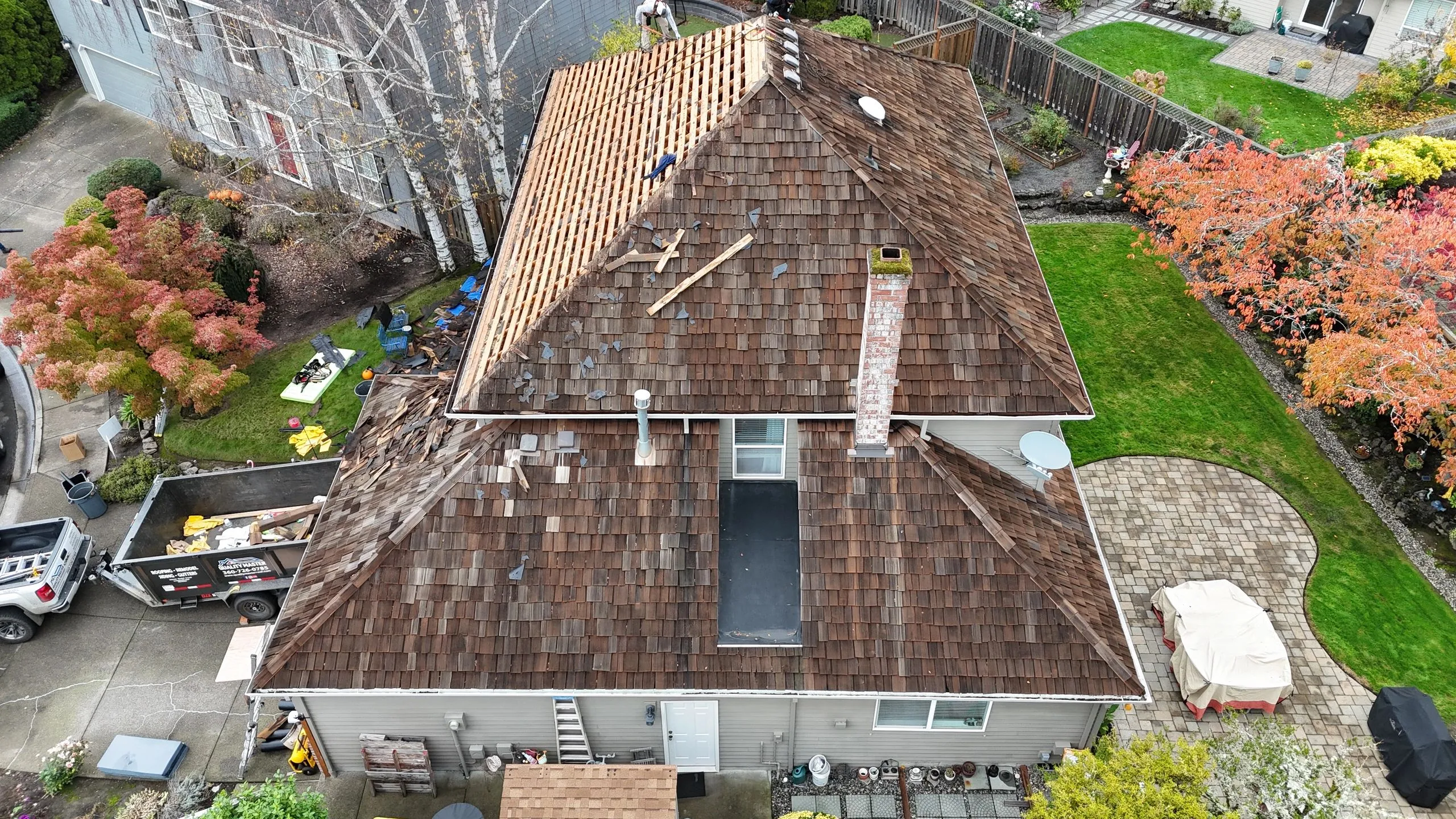 Mid-tear-off drone view of a Ridgefield WA home with decking exposed